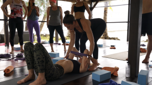 Kat Clayton assisting a yoga student into wheel pose, teaching a yoga workshop on a yoga retreat in Thailand at Samhita Wellness and Yoga Retreat Centre