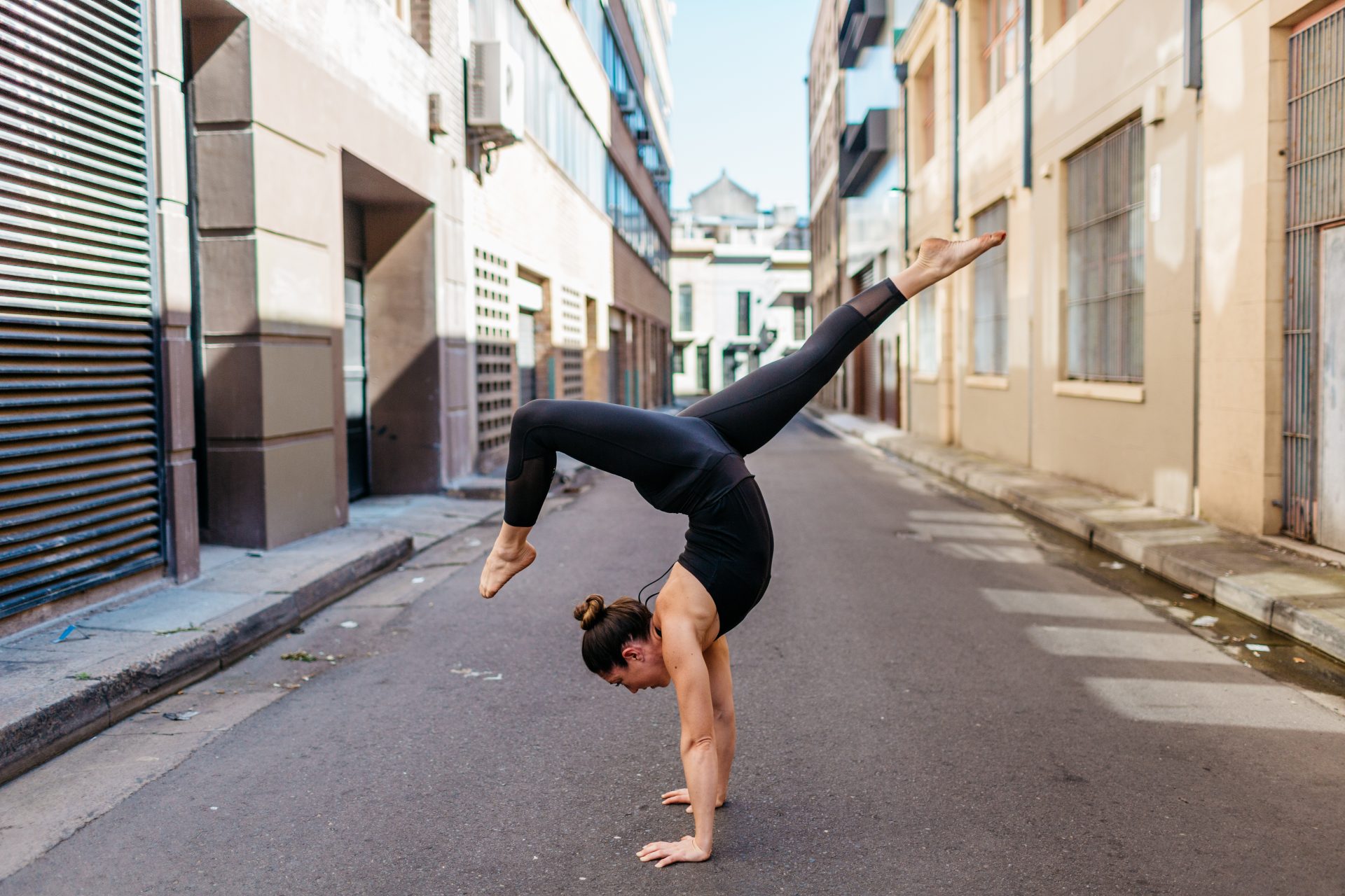 Kat Clayton doing a yoga pose handstand arm balance in an urban city environment Yoga Teacher Kat teaches workshops to learn how to handstand and armbalance