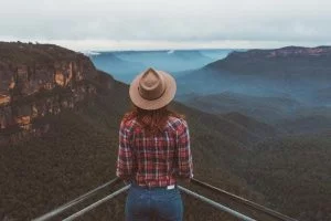 Girl looking out over the blue mountains with a hat