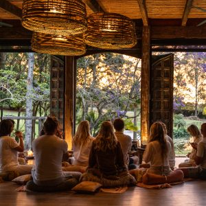 Group of wellness retreat participants enjoying a tea ceremony overlooking the sunset as part of a yoga and wellness retreat in Byron Bay.