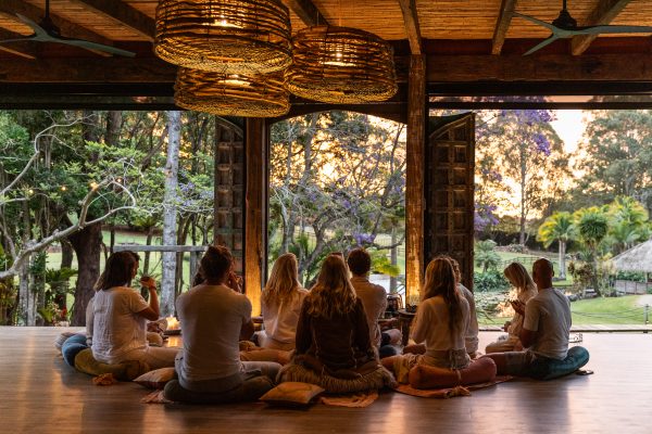 Group of wellness retreat participants enjoying a tea ceremony overlooking the sunset as part of a yoga and wellness retreat in Byron Bay.