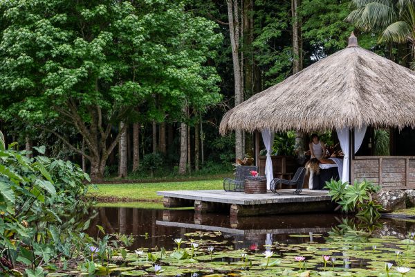 Woman getting a massage at BlueGreen Byron Bay retreat spa overlooking a pond full of lotus flowers and lilypads